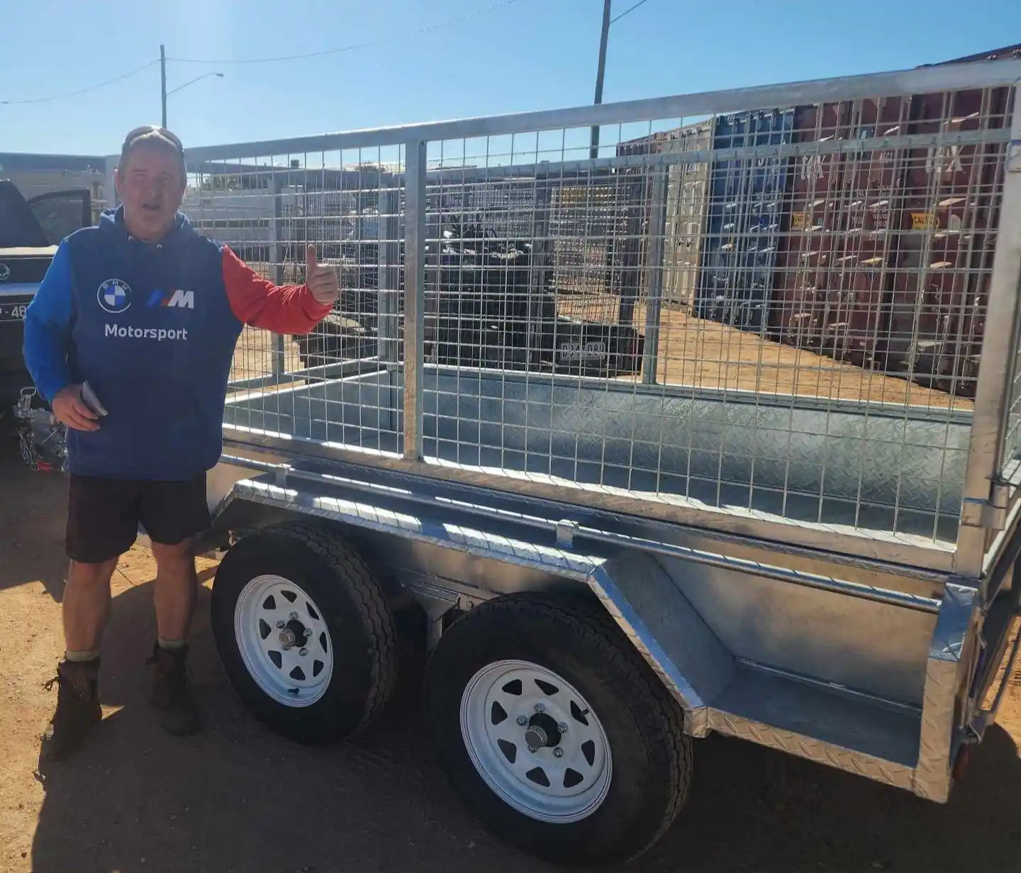 man beside a metal utility trailer